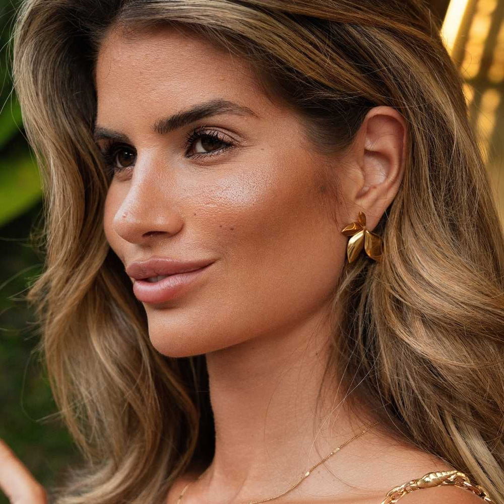 Vrouw draagt gouden waterproof oorbellen van Bay of Hayley